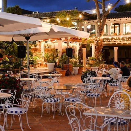 un grupo de personas están sentadas en mesas y sillas en un restaurante al aire libre
