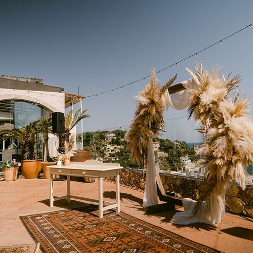 una ceremonia de boda se lleva a cabo en una terraza con un arco y una mesa