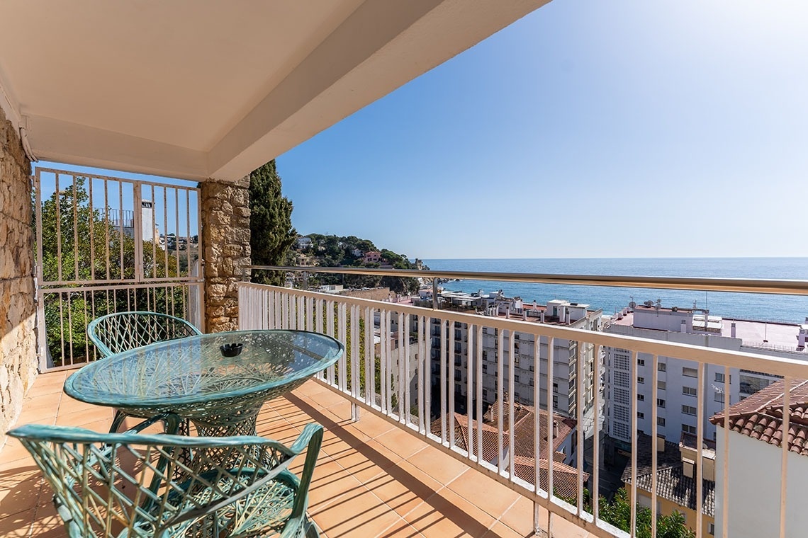 un balcón con una mesa y sillas y una vista al océano