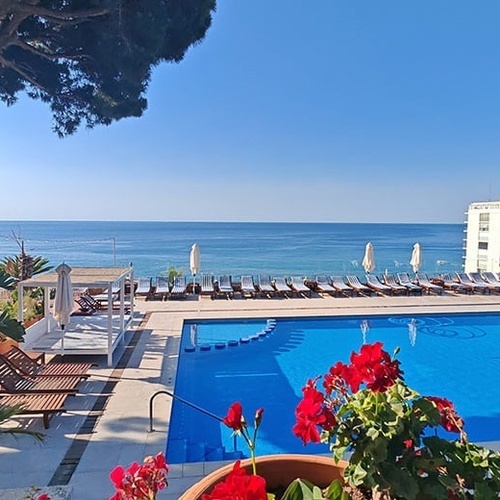 una piscina llena de sillas y sombrillas con vistas al océano
