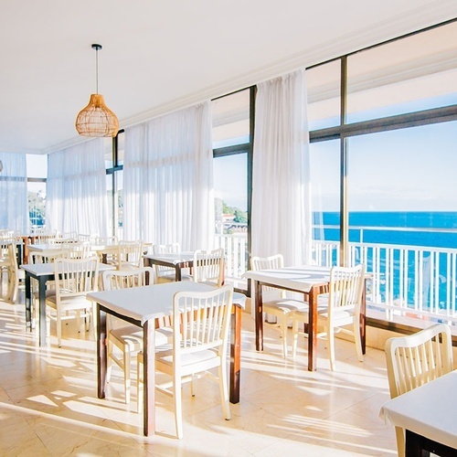 una habitación llena de mesas y sillas con vistas al océano