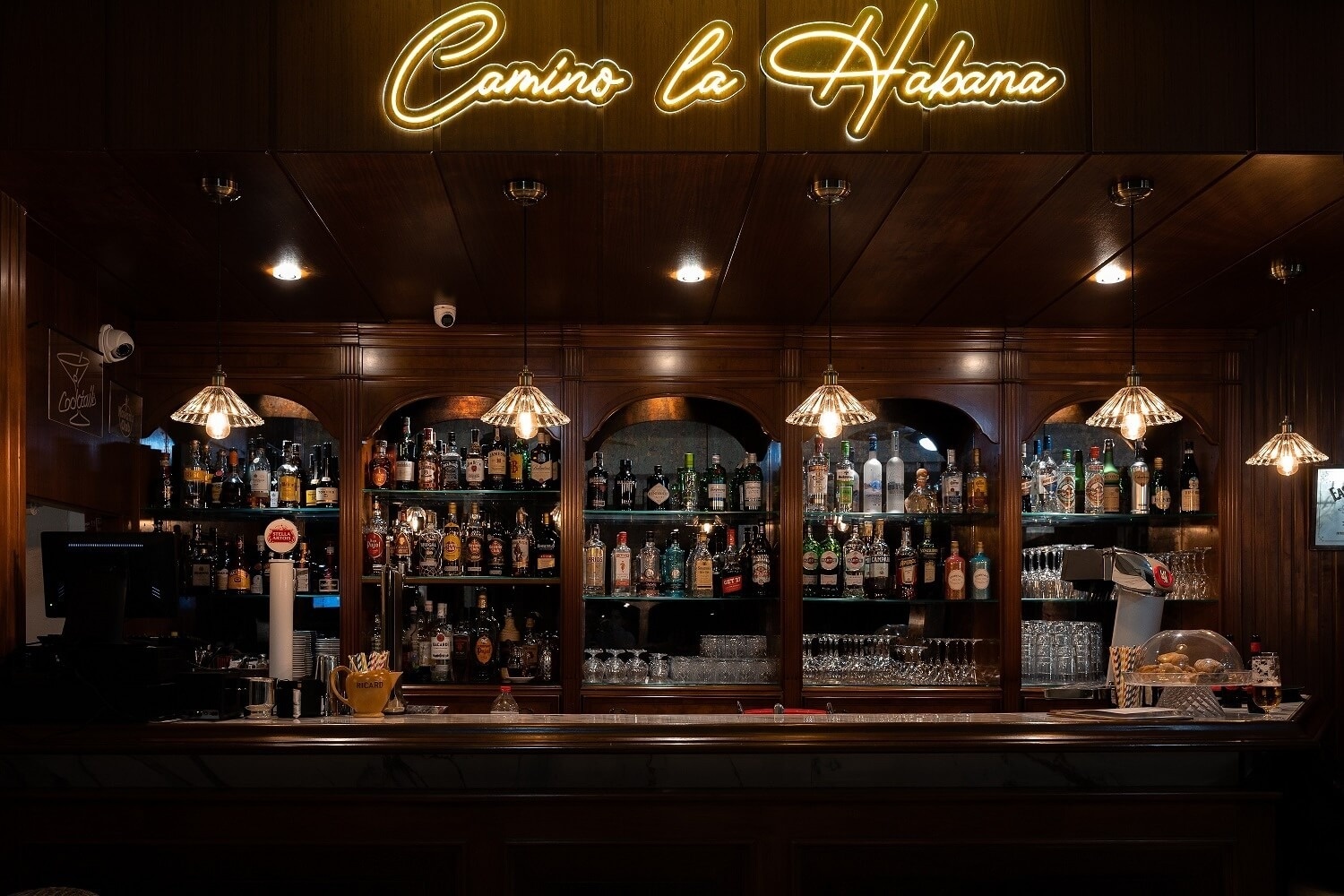 un bar avec des tabourets et des bouteilles sur les étagères