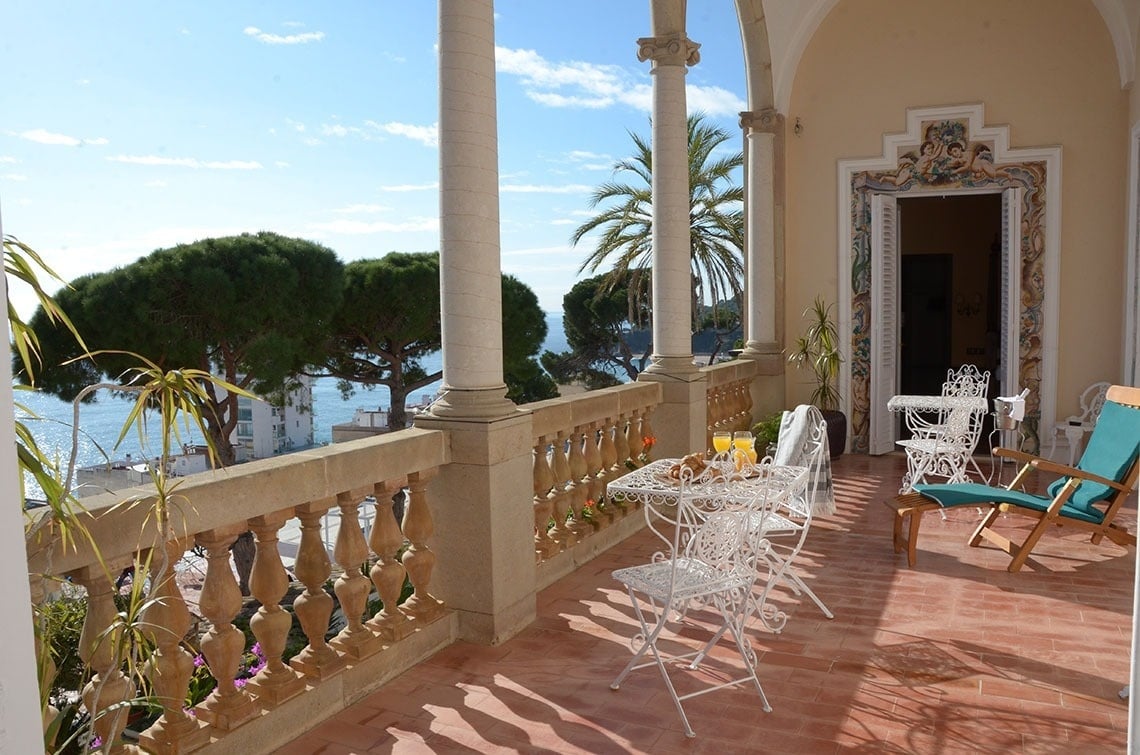 una mesa y sillas en un balcón con vistas al océano