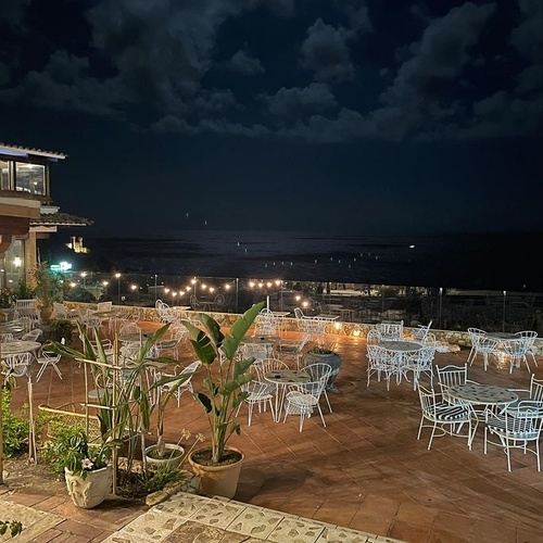 una terraza con muchas mesas y sillas en la noche