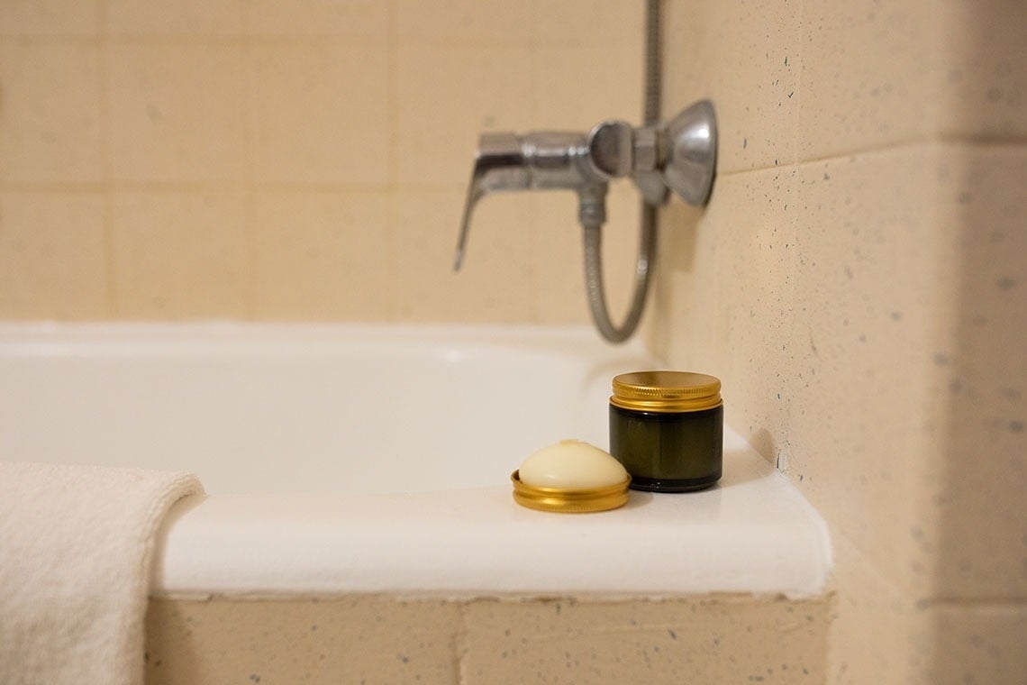 un frasco de jabón y un frasco de crema están en el borde de una bañera