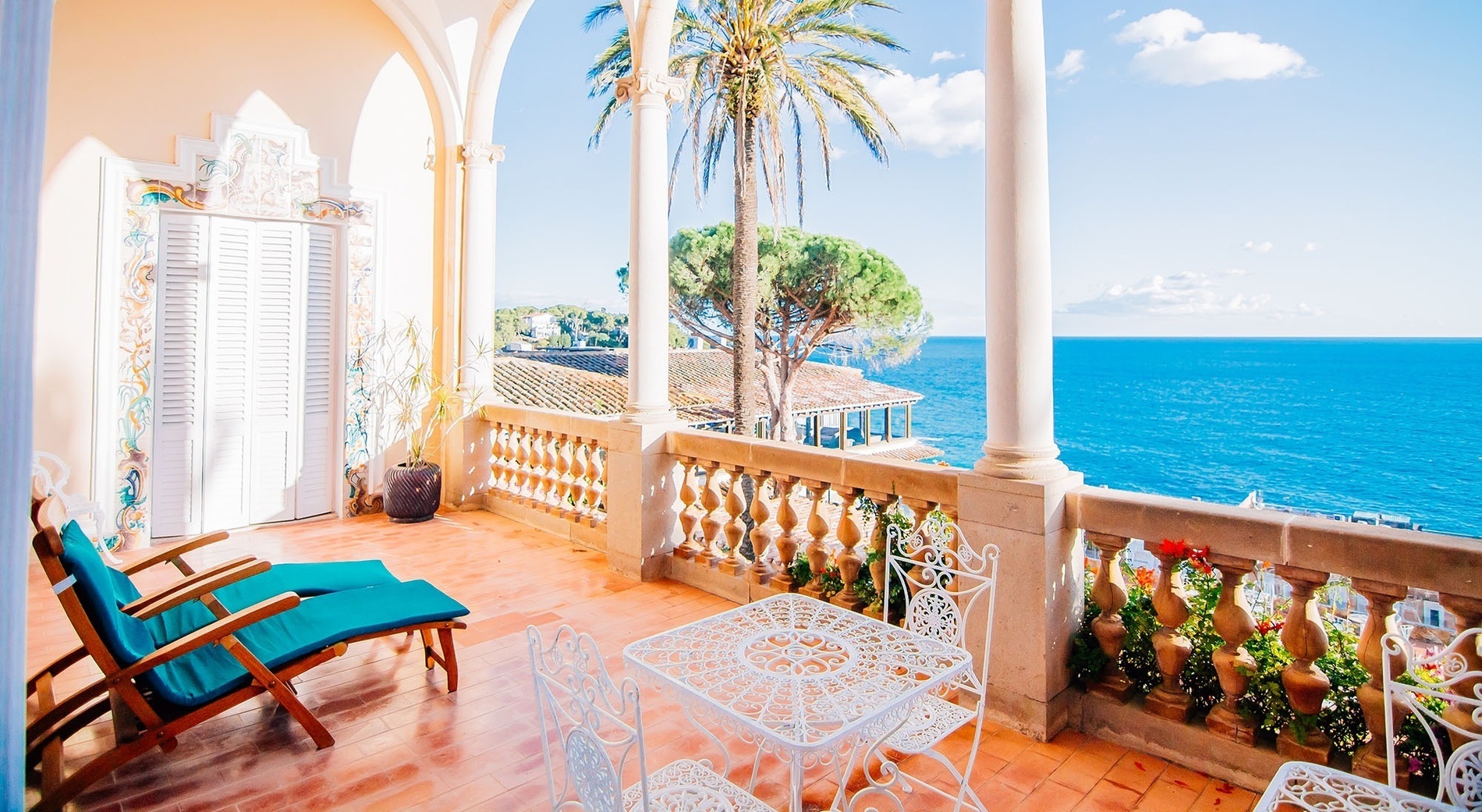 ein Balkon mit Tisch und Stühlen mit Blick auf das Meer