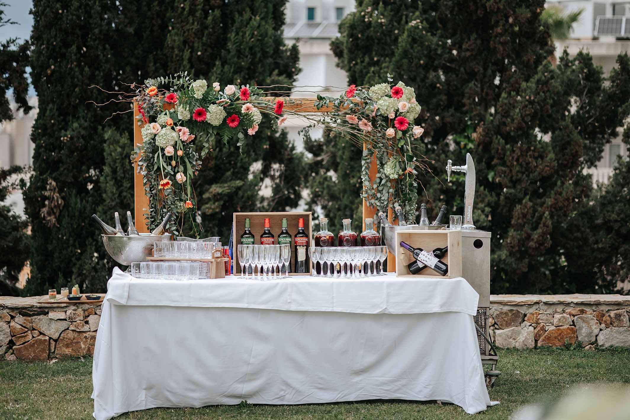 Outdoor bar at Roger De Flor By Seleqtta with floral decor and drinks.