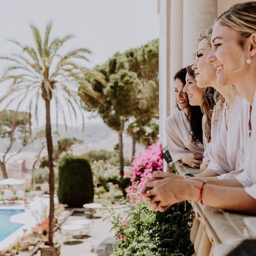 un grupo de mujeres se paran en un balcón mirando a la piscina