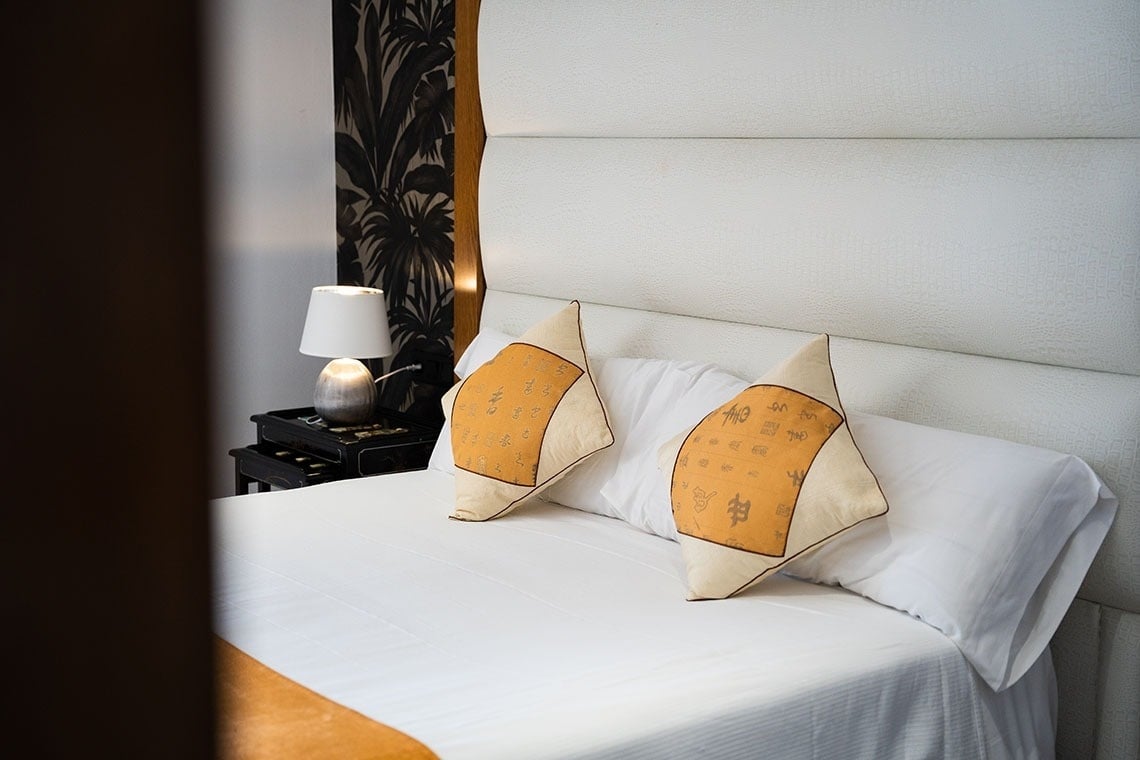 una cama blanca con dos almohadas y una lámpara