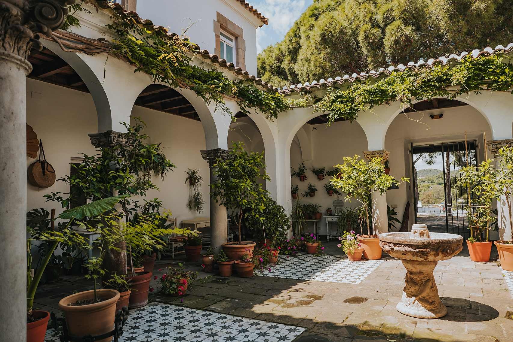 Roger De Flor By Seleqtta patio with fountain and lush plants.