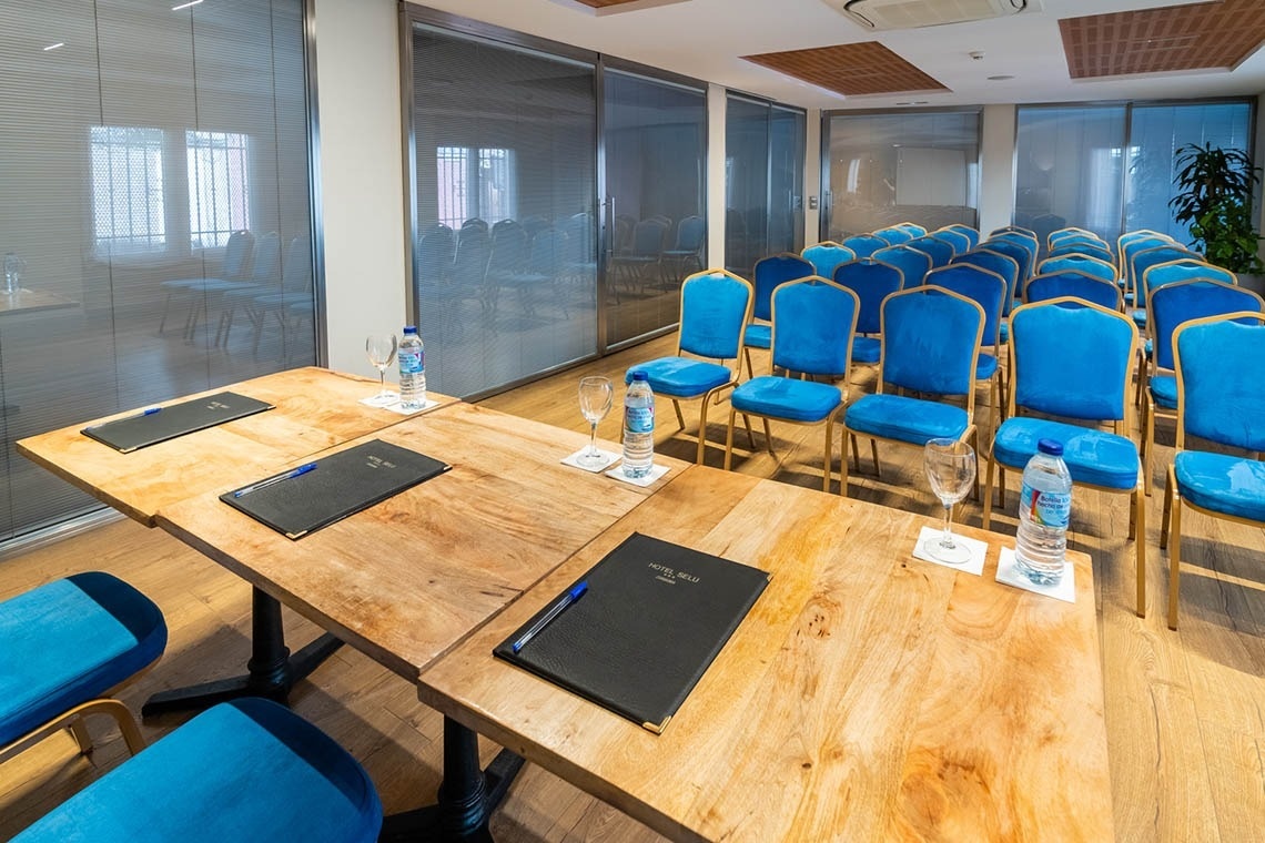 una sala de conferencias con sillas azules y mesas de madera