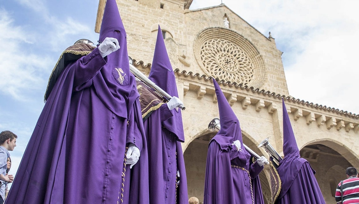 un grupo de hombres en trajes púrpuras parados frente a una iglesia