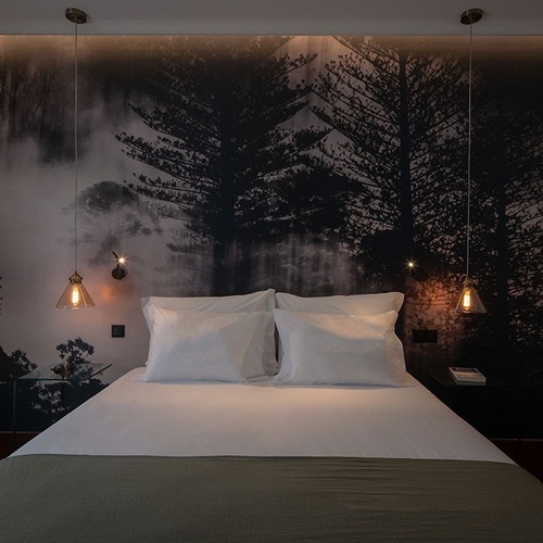 a bedroom with a painting of trees on the wall