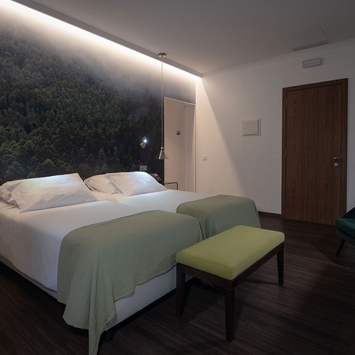 a hotel room with two beds and a green bench