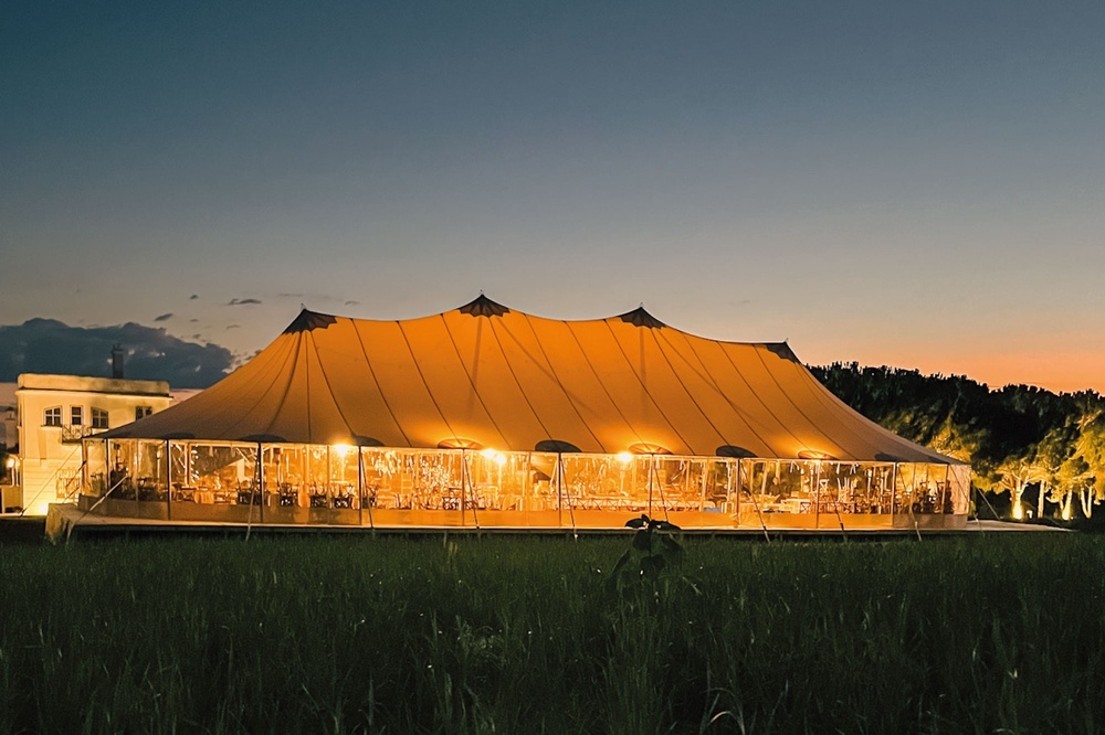 uma grande tenda é iluminada ao entardecer em um campo de grama