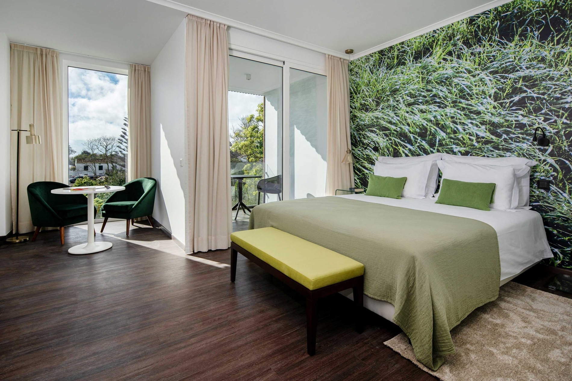 a hotel room with a large bed and a green bench