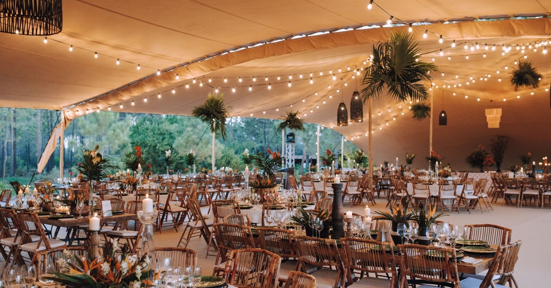 uma grande tenda com mesas e cadeiras decoradas com flores e velas