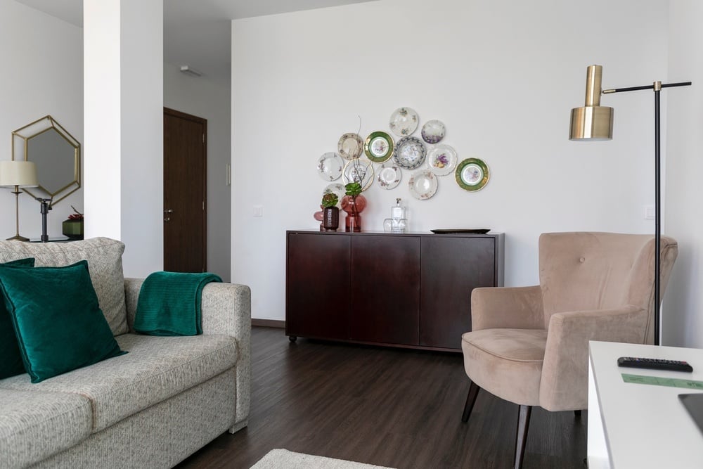 a living room with a couch and chair and plates on the wall