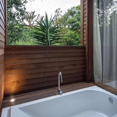 a bathroom with a bathtub and a window with trees in the background