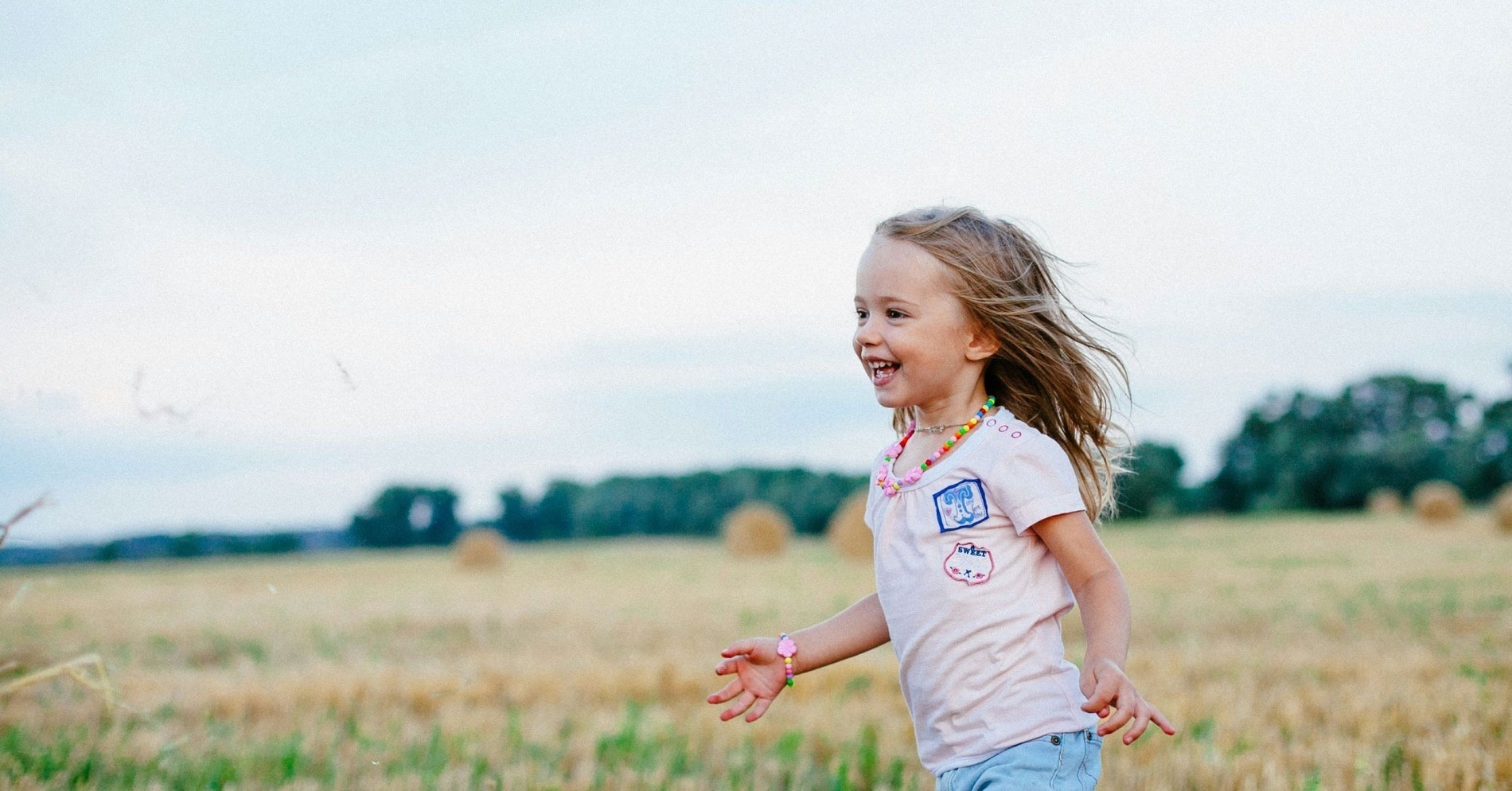 a little girl is picking pink flowers from a bush