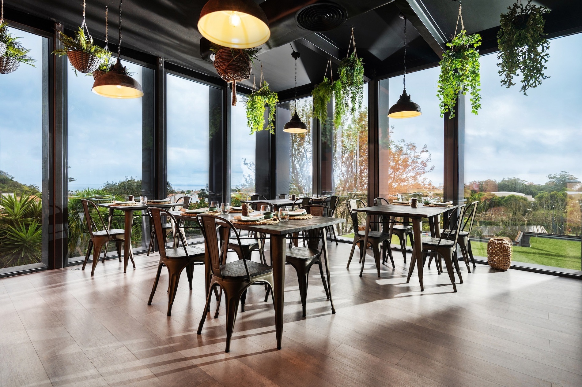 a dining room with tables and chairs and plants hanging from the ceiling