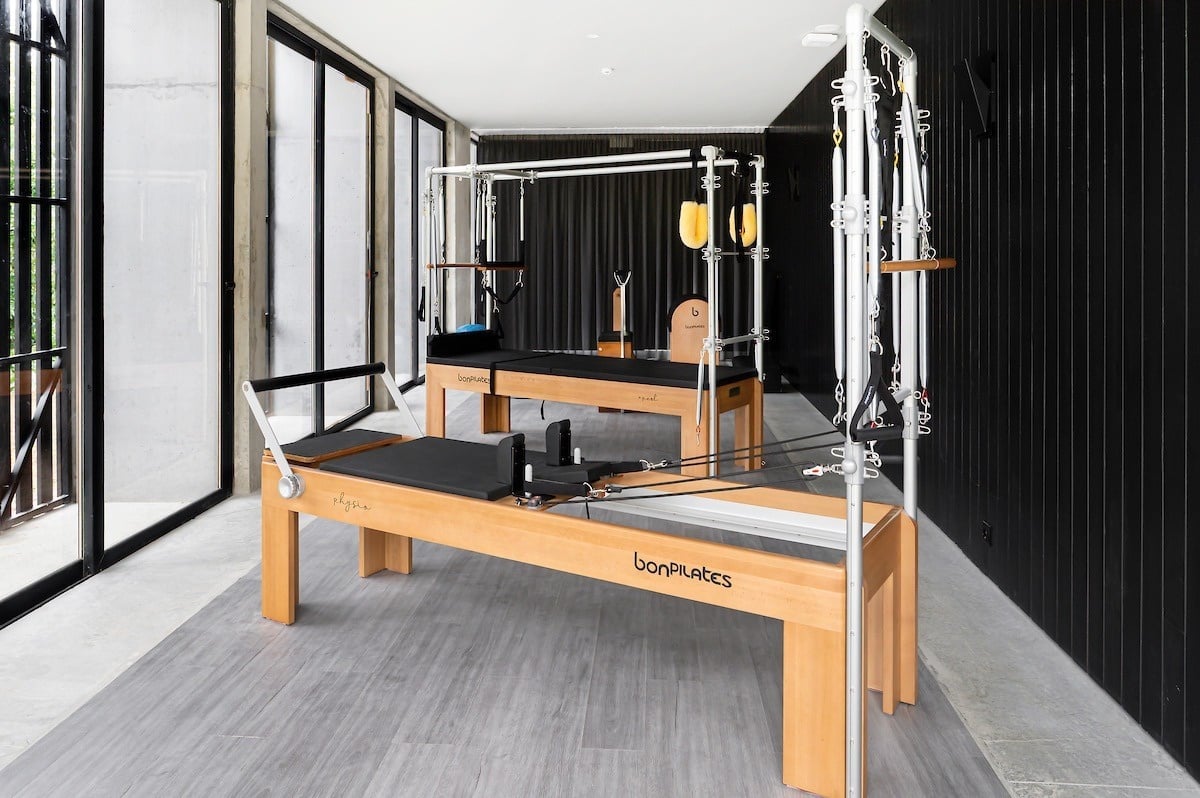 uma mesa de pilates de madeira em uma sala com muitas janelas