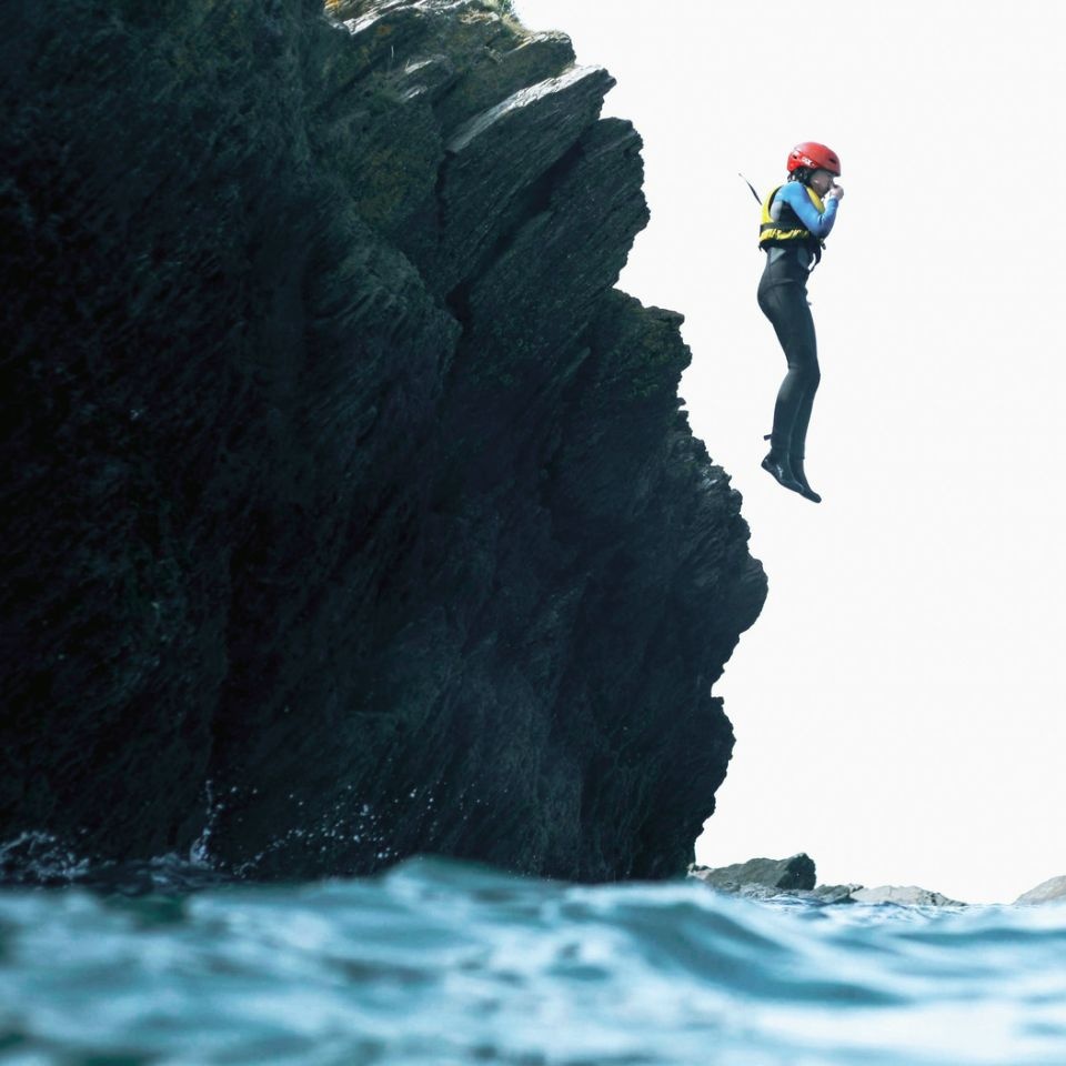 person jumping off a cliff into the sea