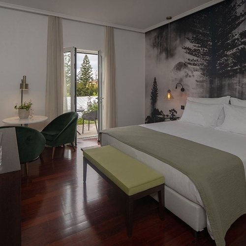 a bedroom with a large bed and a painting of trees on the wall