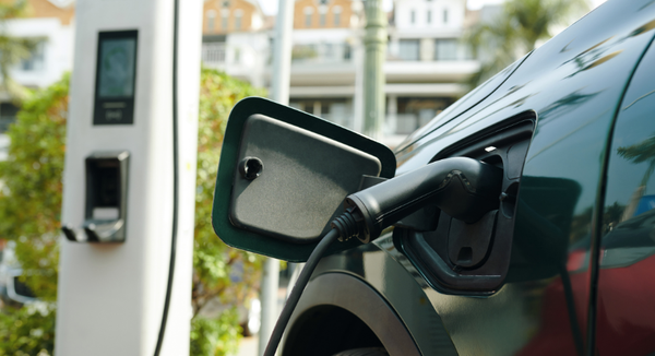 um carro elétrico está sendo carregado em uma estação de carregamento