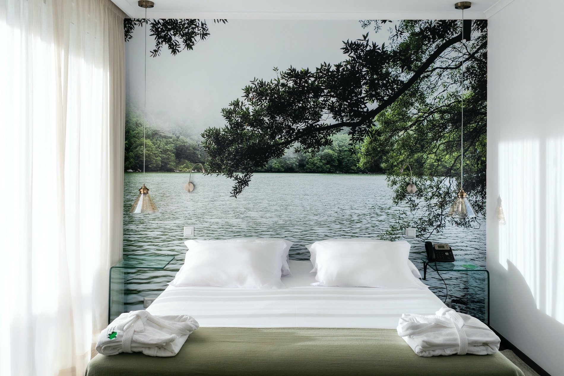 a bed with a picture of a lake behind it