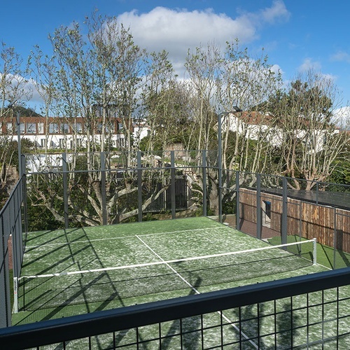 a tennis court with a fence around it and trees in the background