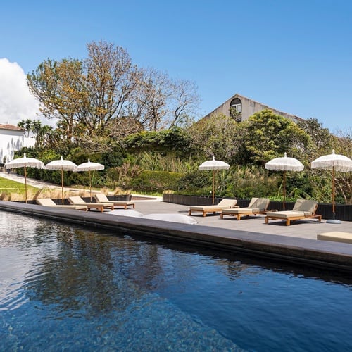 a swimming pool with chairs and umbrellas around it