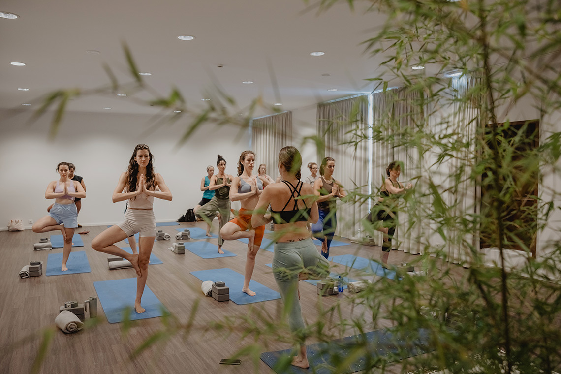 Yoga class in a bright hotel studio with large windows, promotingSenhora da Rosa wellness.
