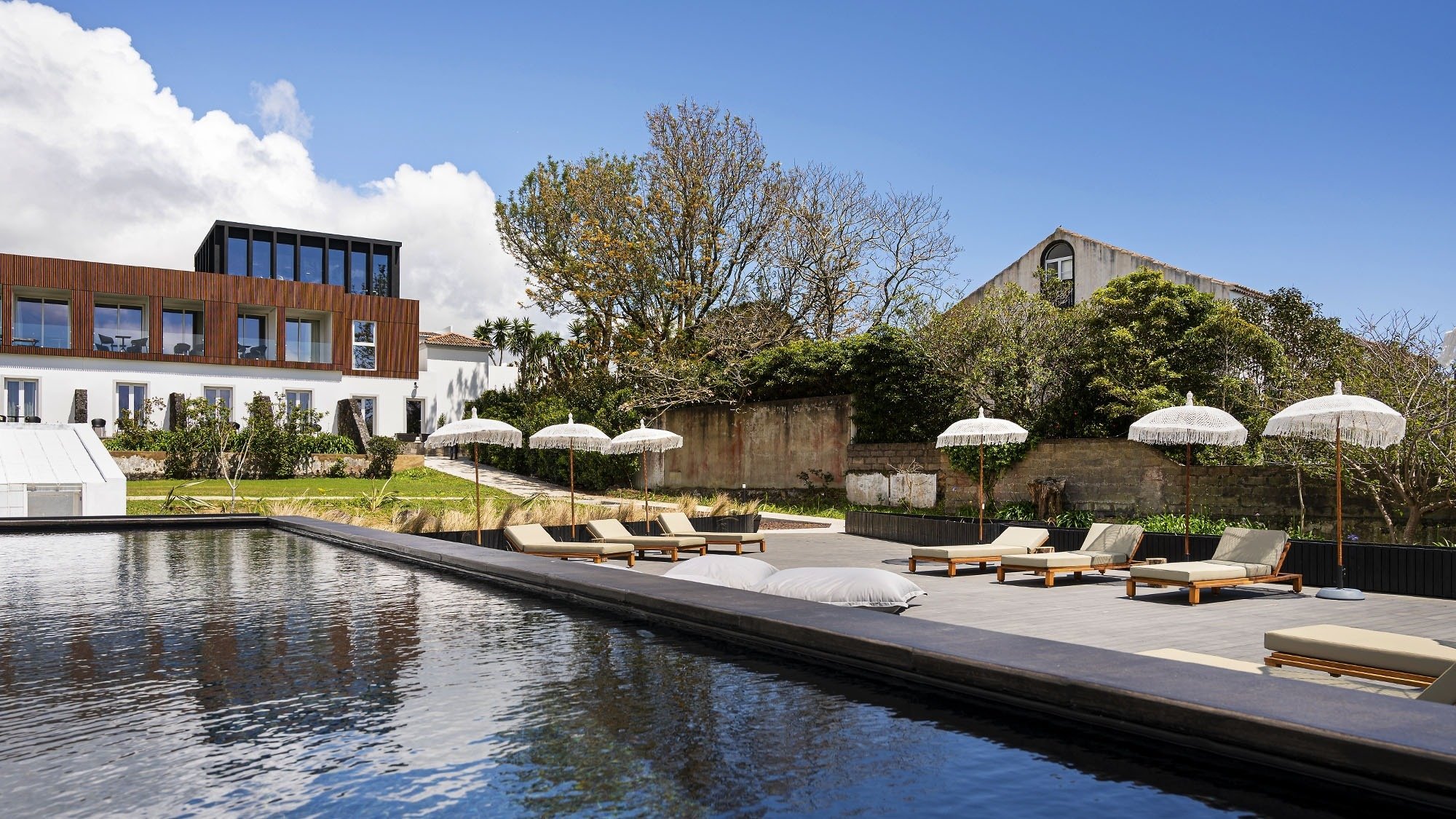 a swimming pool with chairs and umbrellas in front of a building