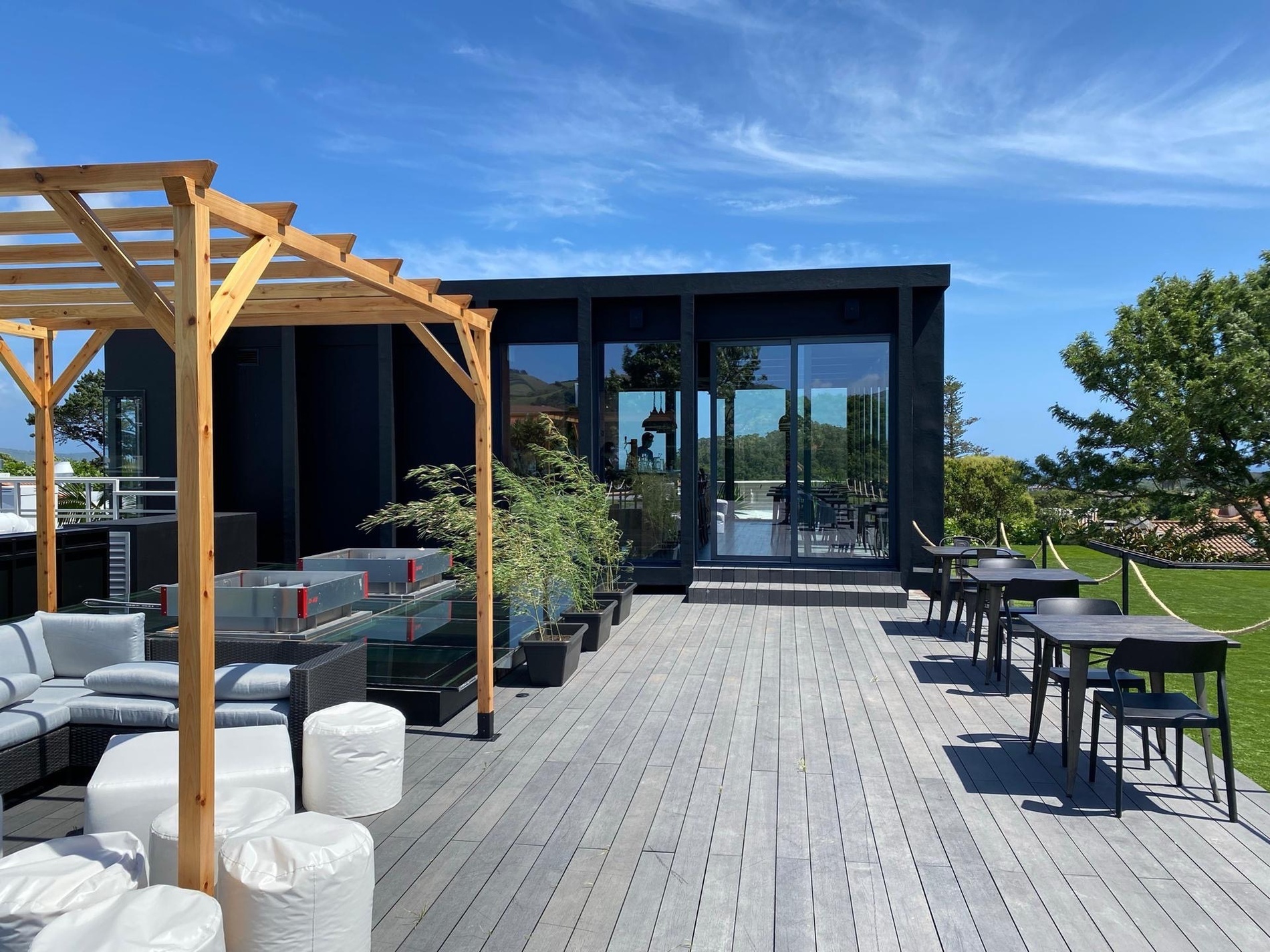 a rooftop deck with tables and chairs and a pergola