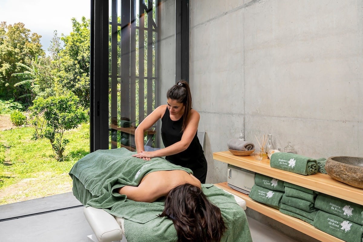 uma mulher está recebendo um massagem em uma mesa com toalhas verdes
