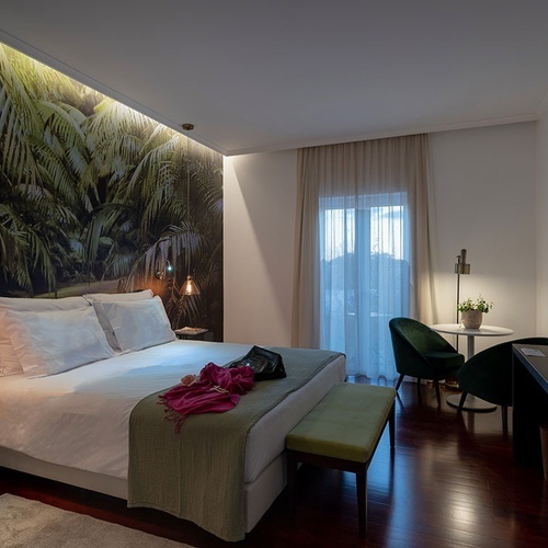 a hotel room with a large bed and a green bench