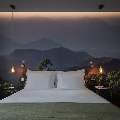 a bedroom with a painting of mountains on the wall