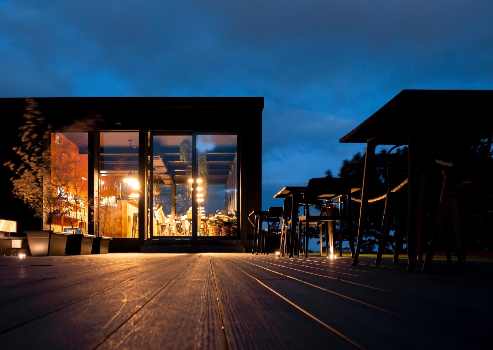 a wooden deck with tables and chairs in front of a building