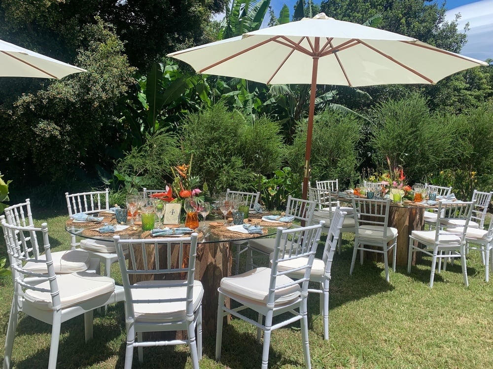 mesas e cadeiras em um jardim com guarda-chuvas