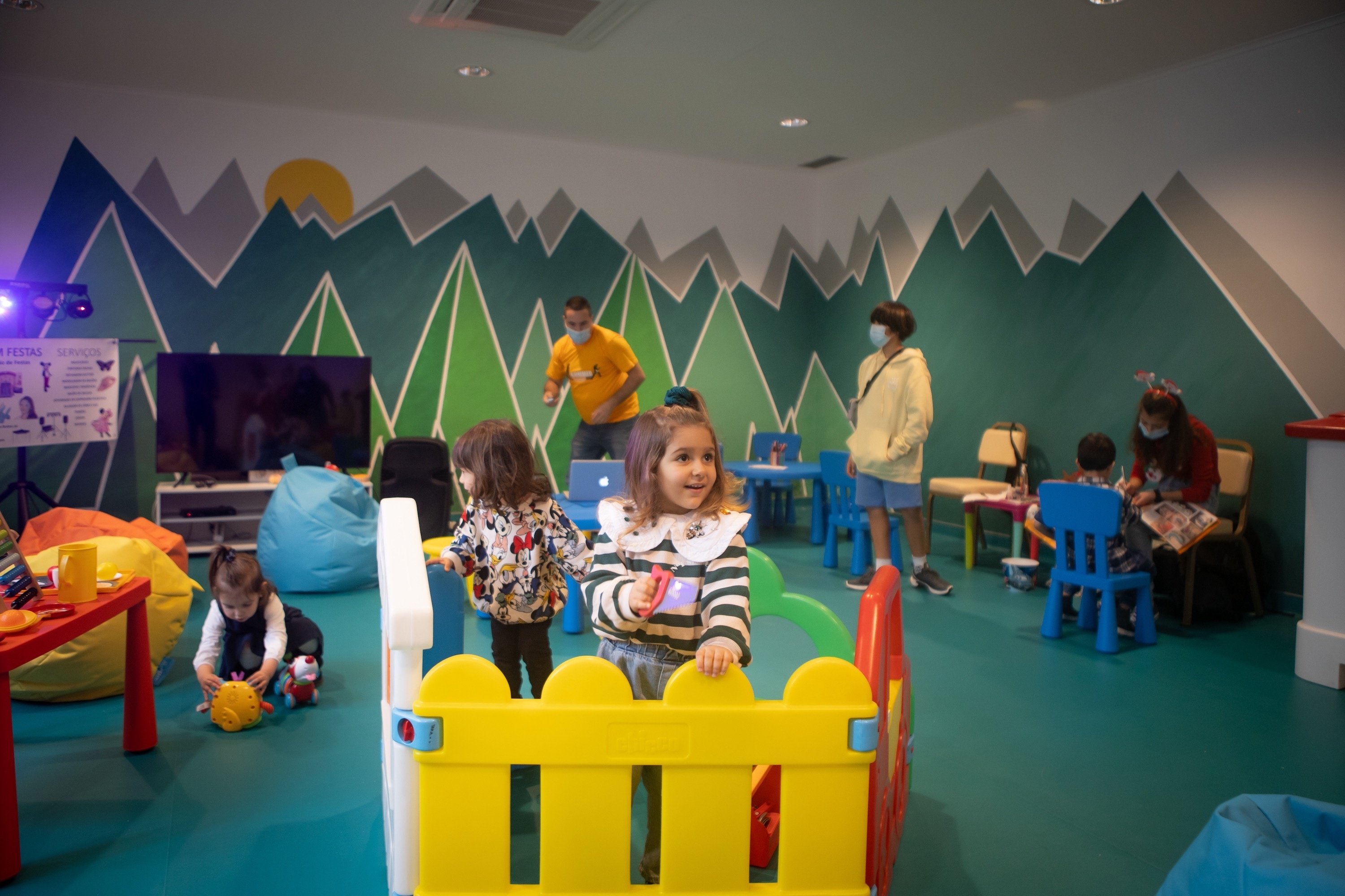 children playing in a room with mountains painted on the wall