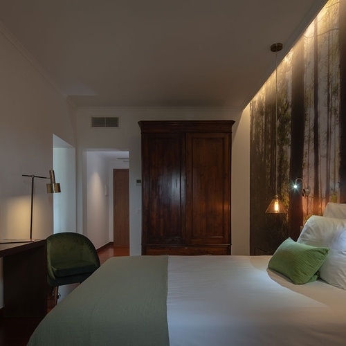 a bedroom with a painting of trees on the wall