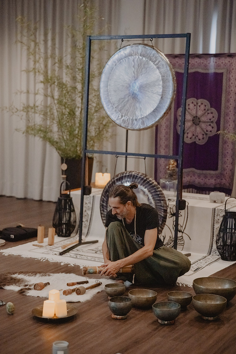 Man playing Tibetan singing bowls at a sound healing session Senhora da Rosa.