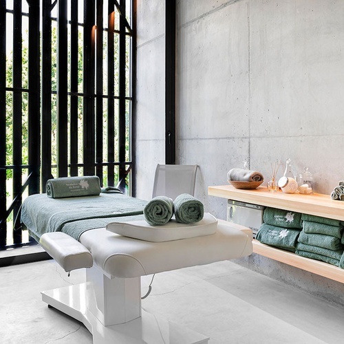 a massage table in a spa with green towels that say ' ayurveda ' on them