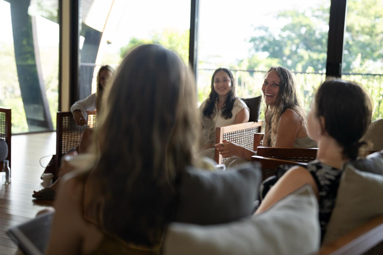 Women chatting and laughing in a stylish hotel lounge with lush green views. Senhora da Rosa