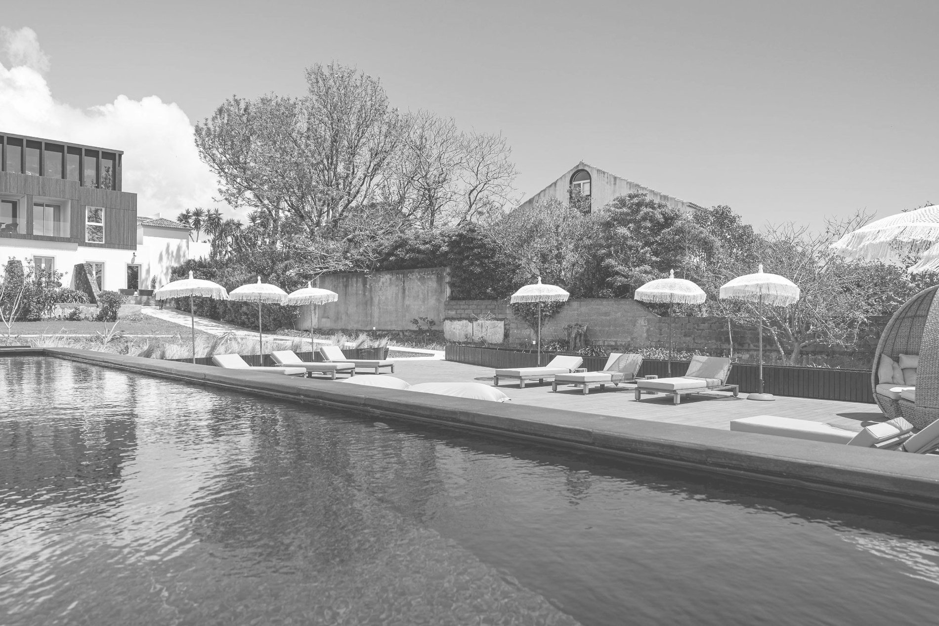 uma foto em preto e branco de uma piscina com cadeiras e guarda-chuvas=s1900