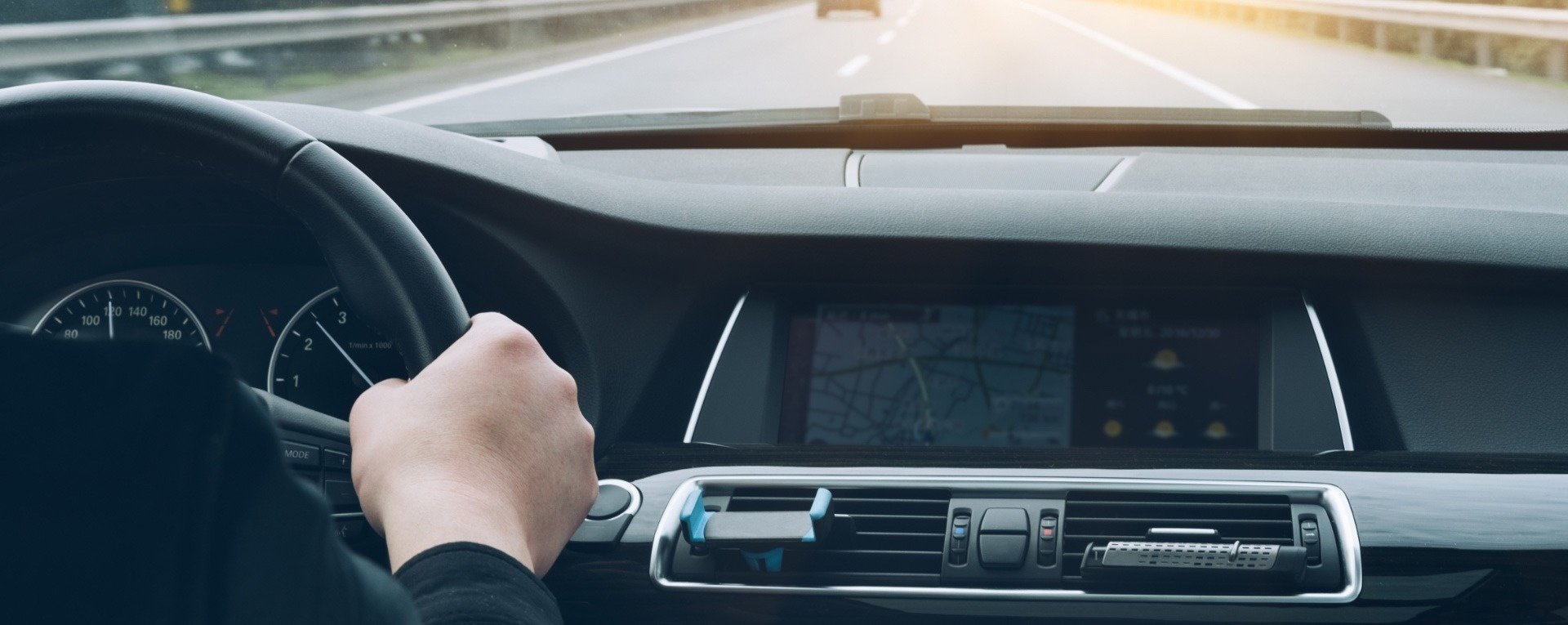 una persona conduce un automóvil en la carretera con el volante en la mano