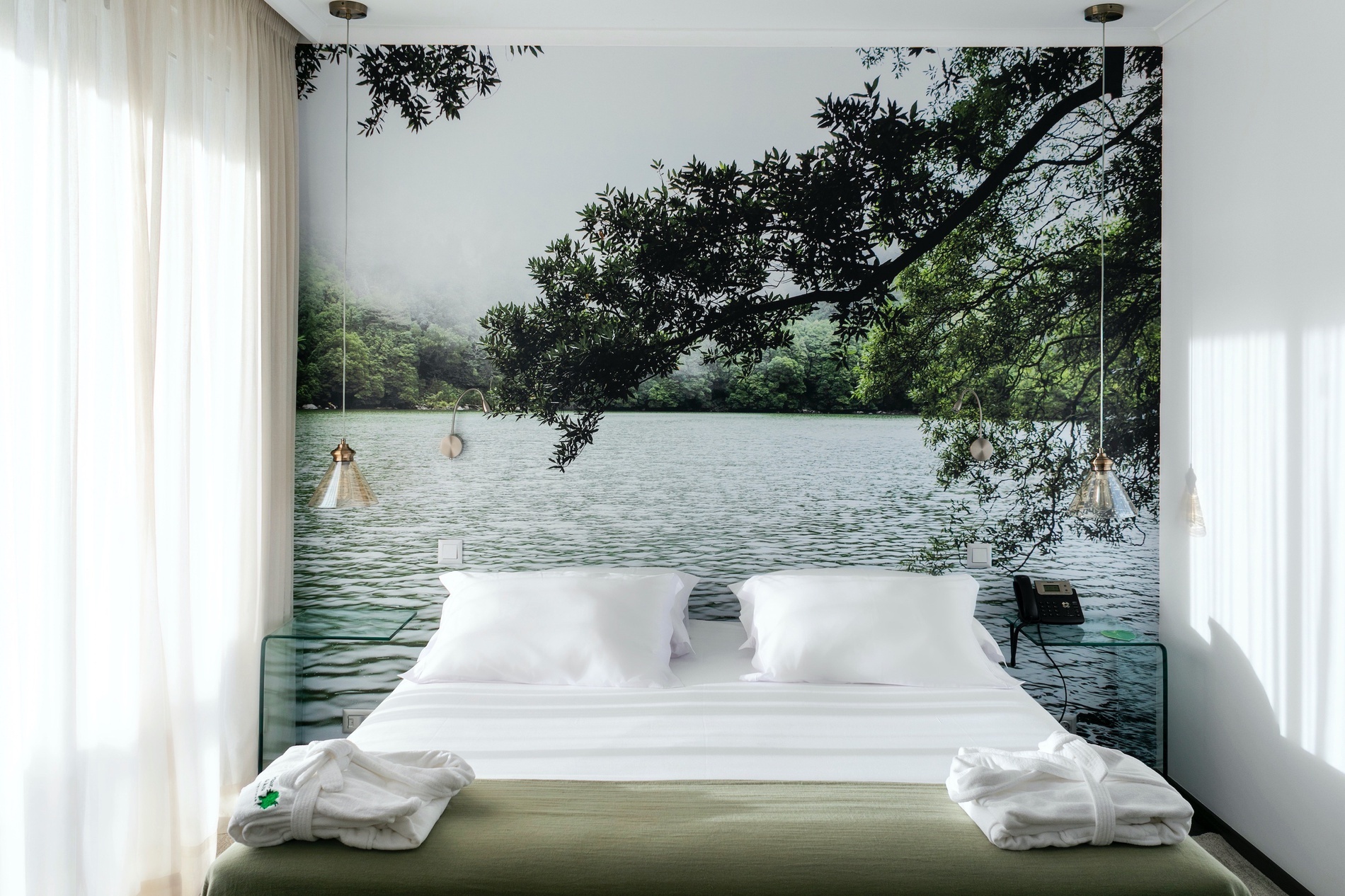 a bed with a picture of a lake behind it