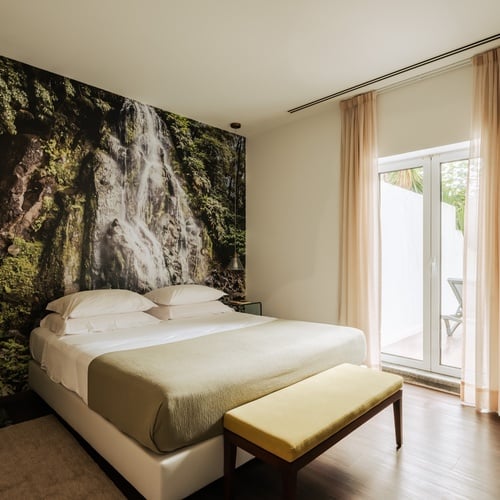 a bedroom with a waterfall wallpaper on the wall