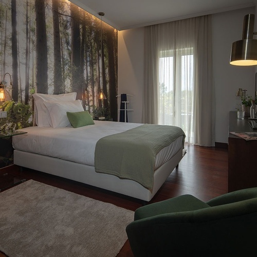 a bedroom with a painting of trees on the wall